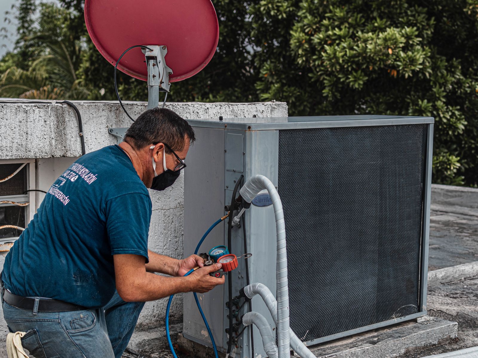 An HVAC technician servicing an outdoor air conditioning unit